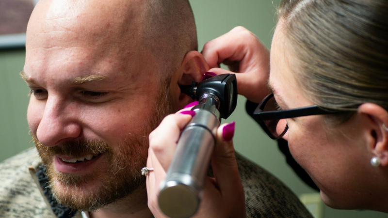 Ārsts vizītes laikā pacientam parbauda dzirdi